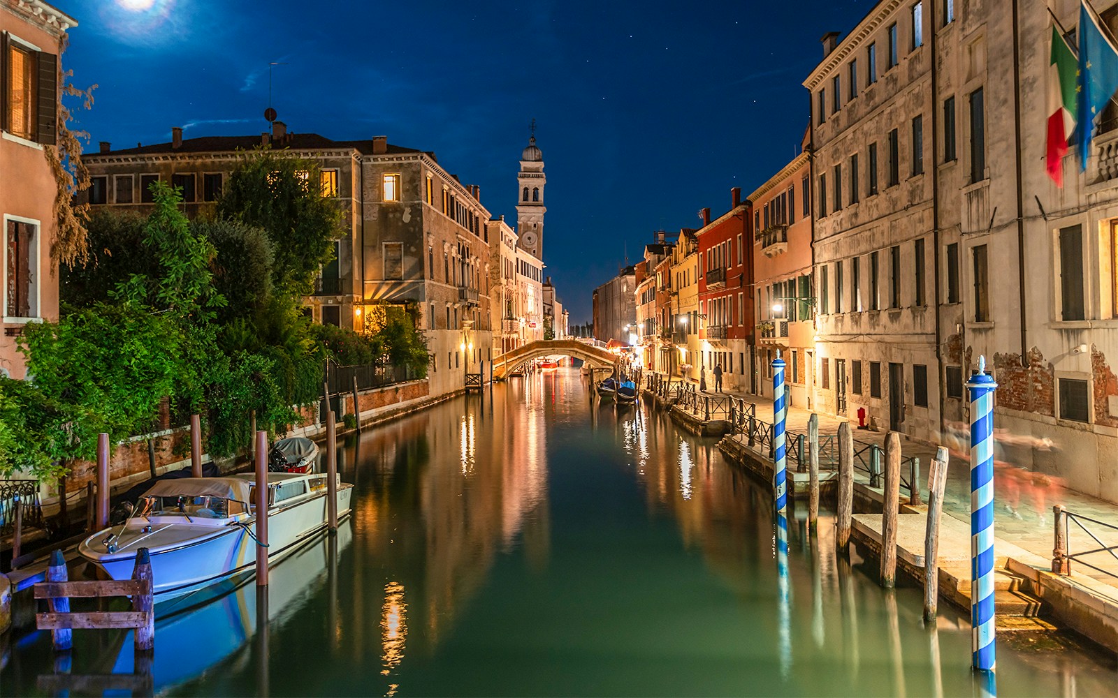 Night view of a canal in Venice with gondolas and illuminated buildings.