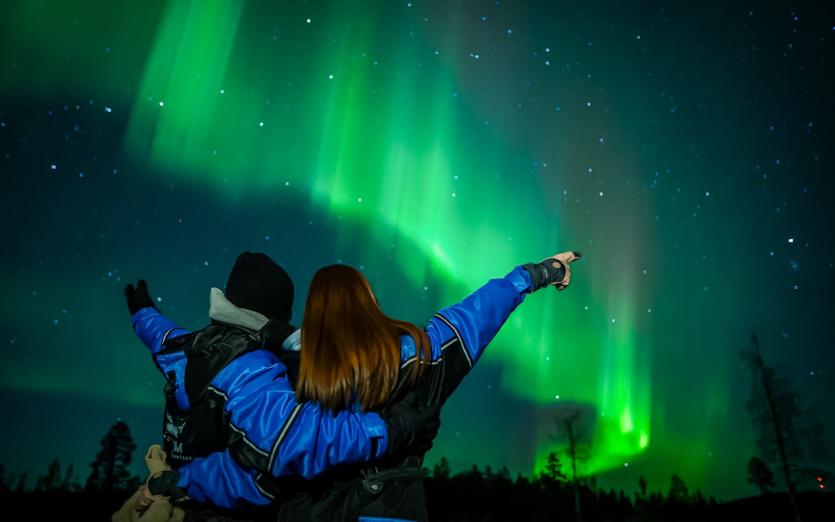 Couple watching Northern Lights in Levi, Finland.