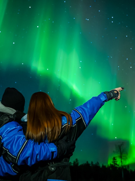 Couple watching Northern Lights in Levi, Finland.