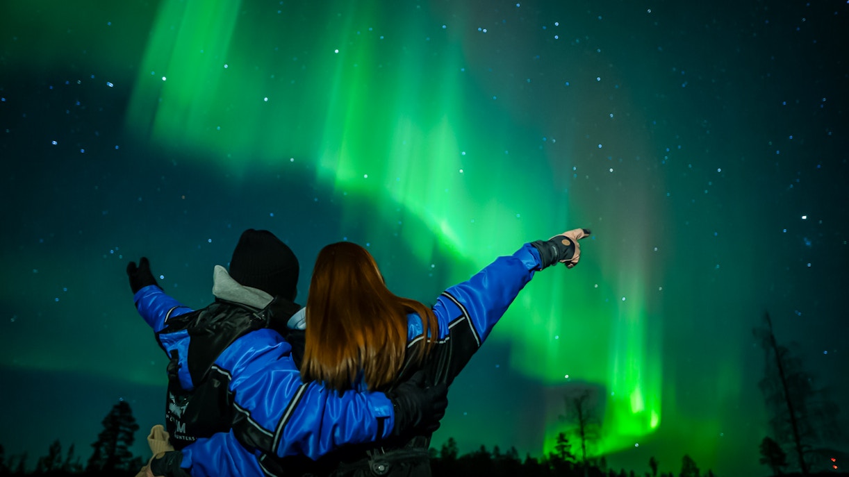 Couple watching Northern Lights in Levi, Finland.