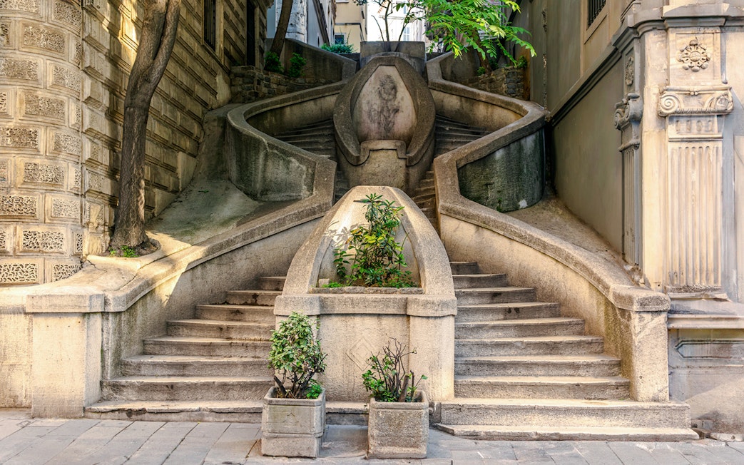 Staircase leading to Galata Tower, Istanbul, with plants and stone architecture.