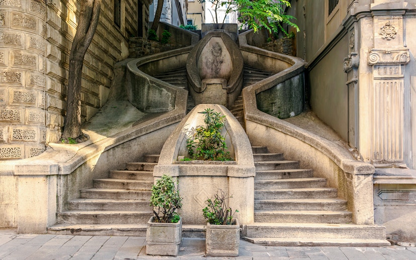 Staircase leading to Galata Tower, Istanbul, with plants and stone architecture.