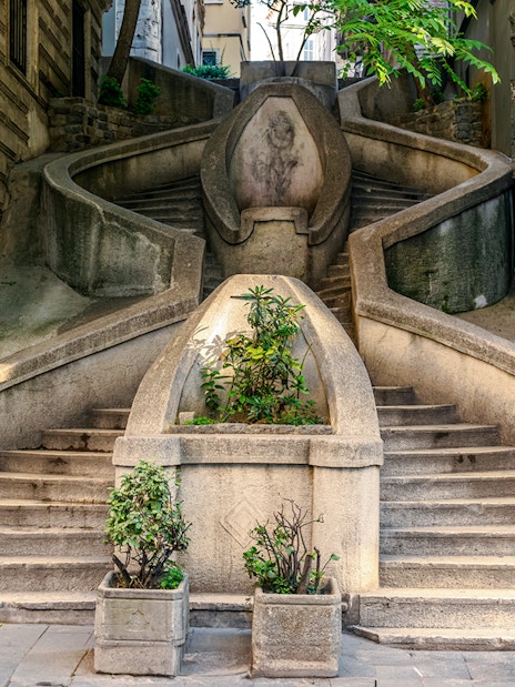 Staircase leading to Galata Tower, Istanbul, with plants and stone architecture.