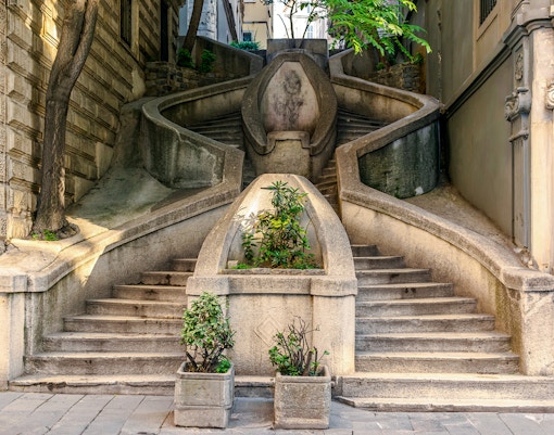 Staircase leading to Galata Tower, Istanbul, with plants and stone architecture.
