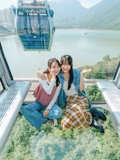 People enjoying a ride in a standard cable car at Ngong Ping, overlooking lush landscapes.