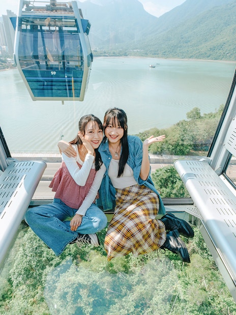 People enjoying a ride in a standard cable car at Ngong Ping, overlooking lush landscapes.