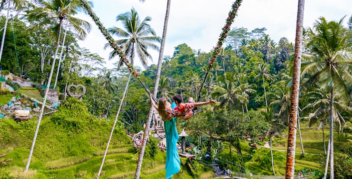 Couple on a swing overlooking rice terraces at Alas Harum, Bali.