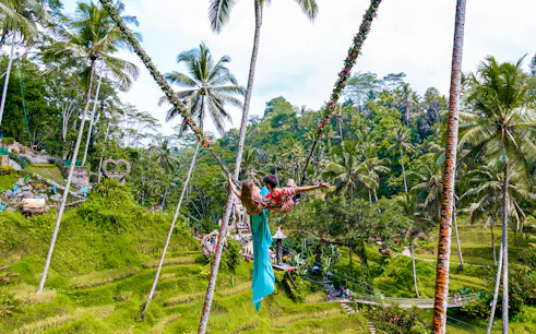 Couple on a swing overlooking rice terraces at Alas Harum, Bali.
