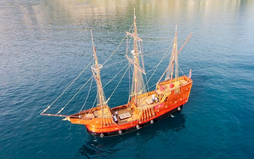 Game of Thrones ship replica sailing on clear blue waters.