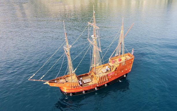 Game of Thrones ship replica sailing on clear blue waters.
