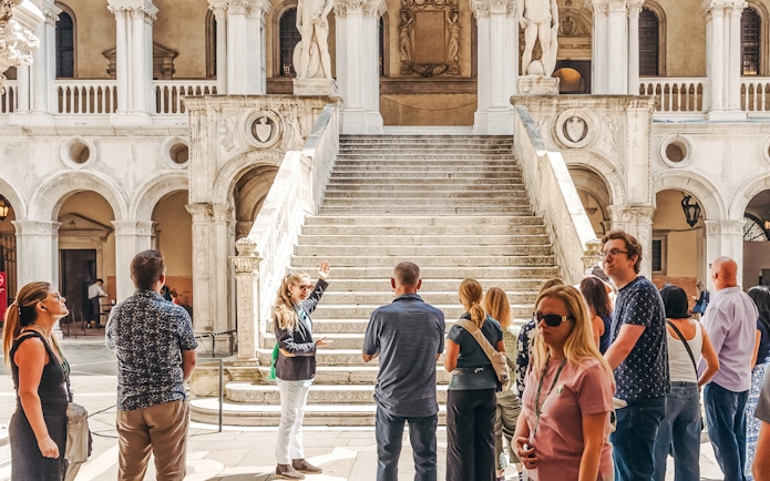 Tour group near Giants' Staircase at Doge's Palace, Venice, with guide explaining architecture.