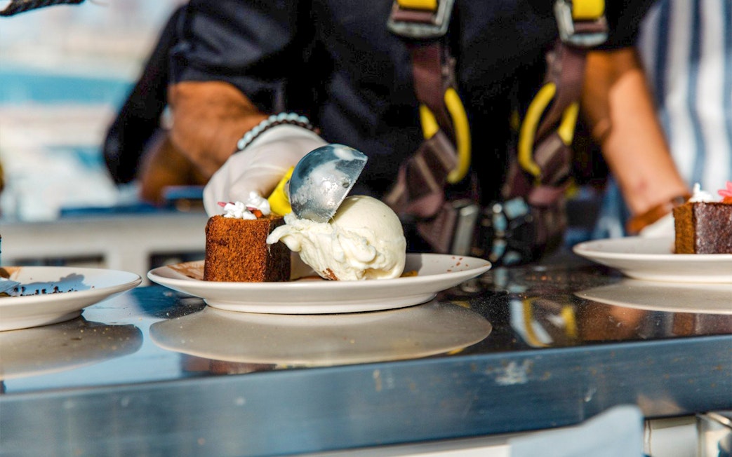 Scooping ice cream onto cake during Dinner in the Sky experience.