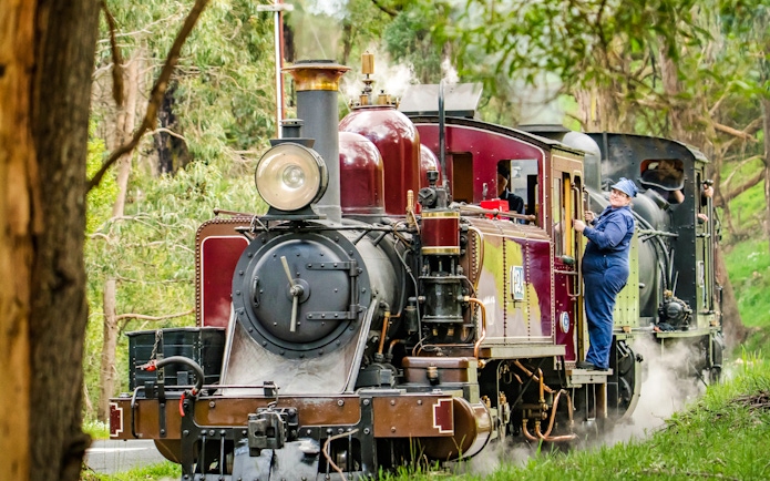 Puffing Billy steam train with crew member in Melbourne forest.