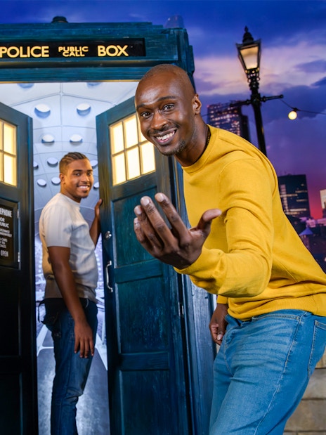 TARDIS with Doctor Who figure at Madame Tussauds, London skyline in background.