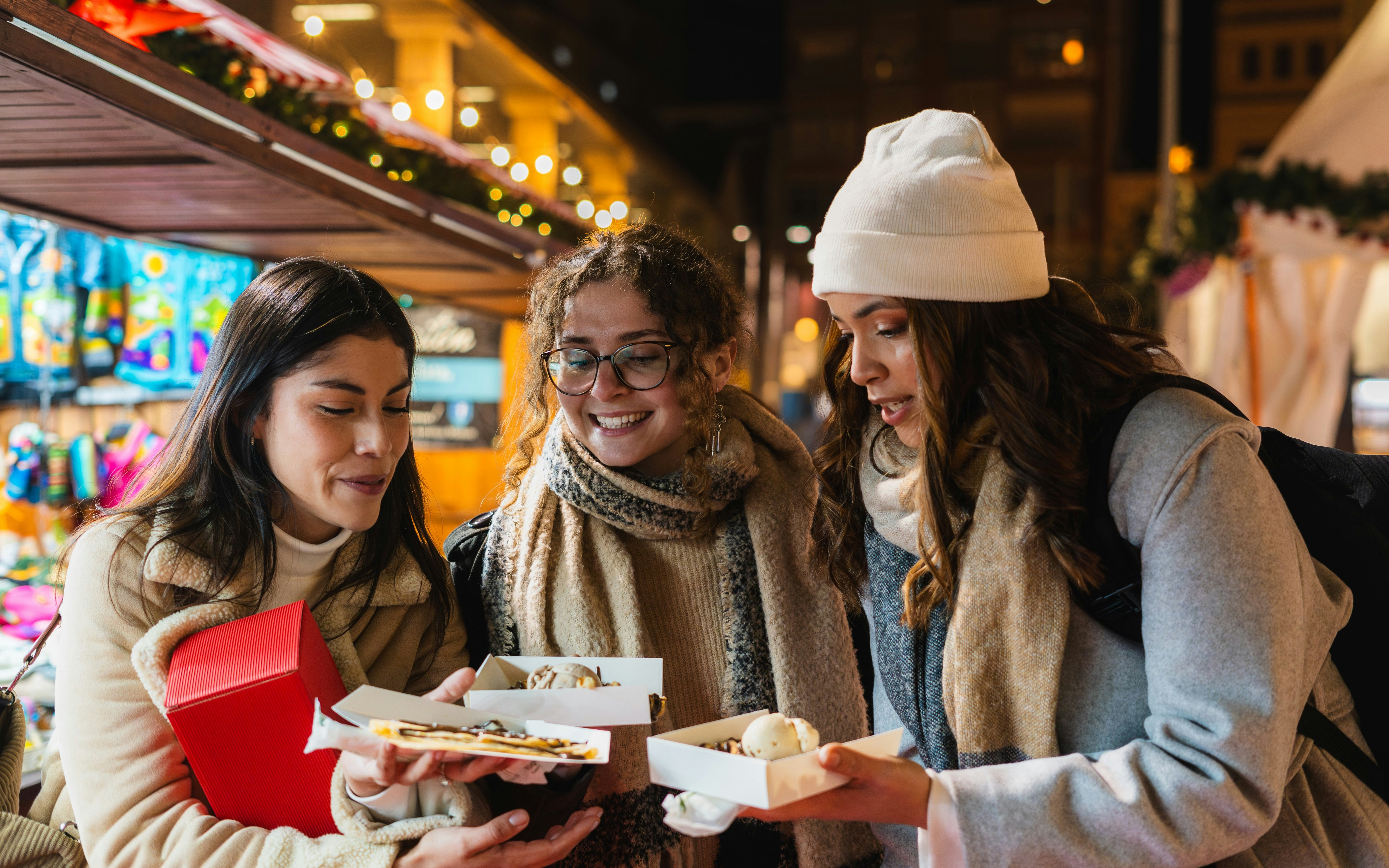 Friends enjoying desserts at a market food stall at night.