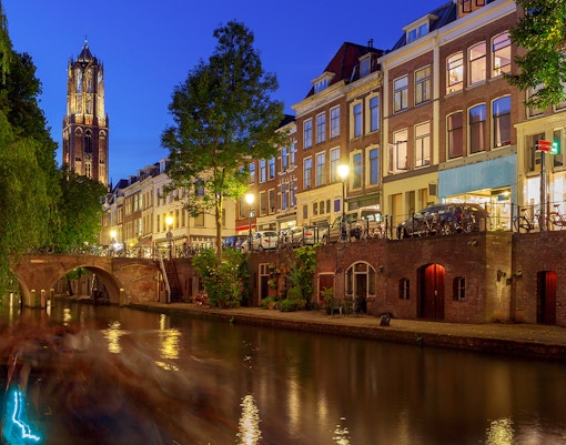Utrecht canal at night with Dom Tower and historic buildings.
