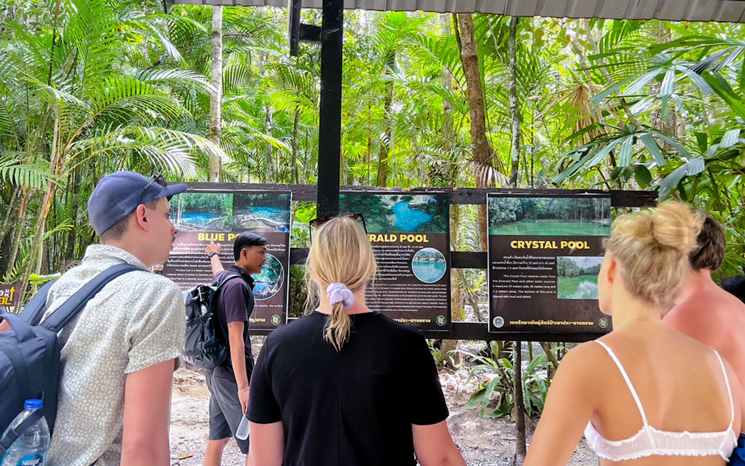 Guests reading information boards at Emerald Pools and Hot Spring, Krabi, Thailand.