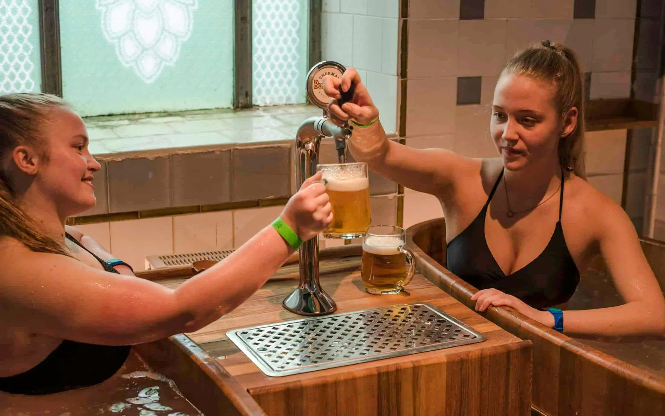 Guests enjoying beer in wooden tubs at Szechenyi Spa Beer Spa, Budapest.