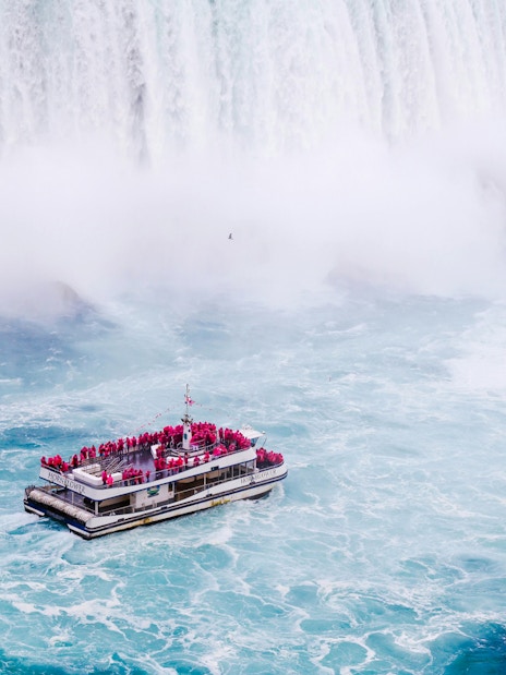 Tourist boat near the base of Niagara Falls surrounded by mist and churning water.