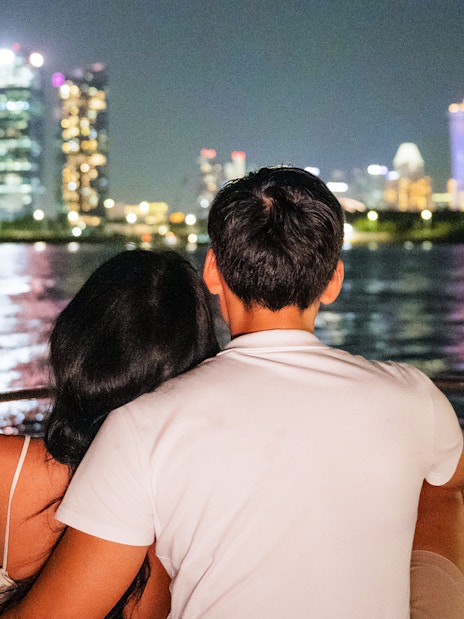 Couple on yacht enjoying Marina Bay Sands skyline at night.