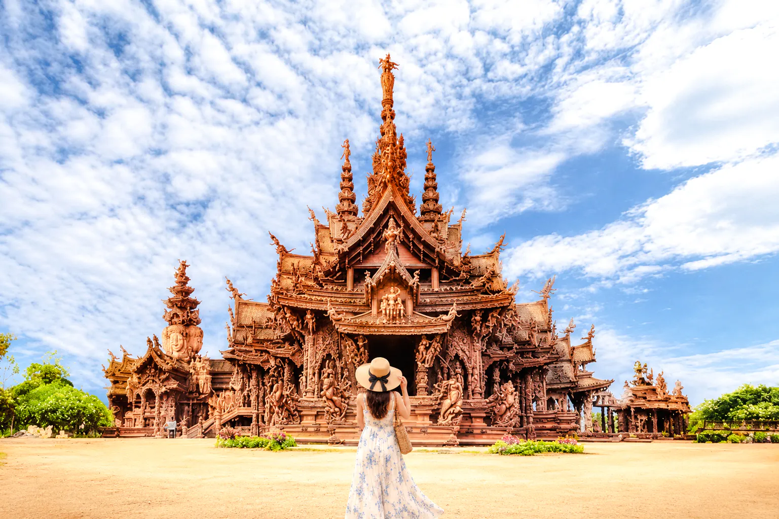 Sanctuary of Truth in Pattaya with visitor in foreground, clear sky above.
