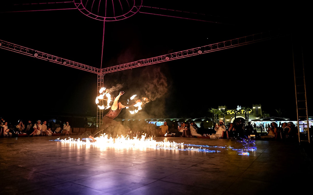 Fire performer at evening desert safari show, surrounded by audience, Dubai.