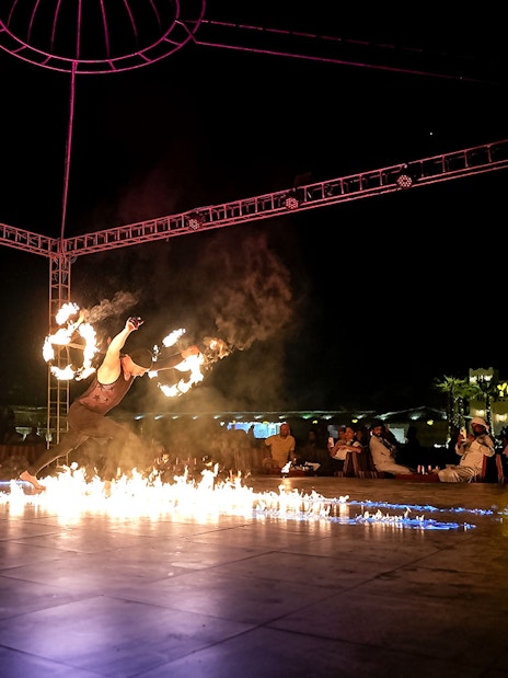 Fire performer at evening desert safari show, surrounded by audience, Dubai.