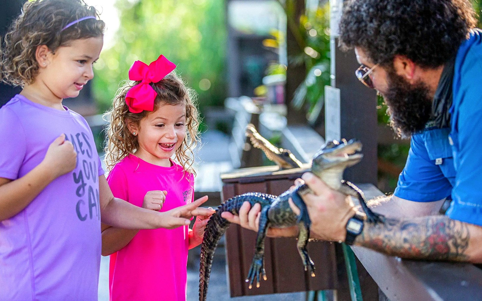 Children interacting with a small alligator at Everglades reptile exhibit.