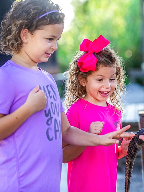 Children interacting with a small alligator at Everglades reptile exhibit.