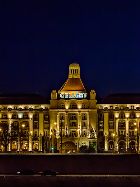 Gellert Bath illuminated at night, viewed from the Danube River in Budapest.