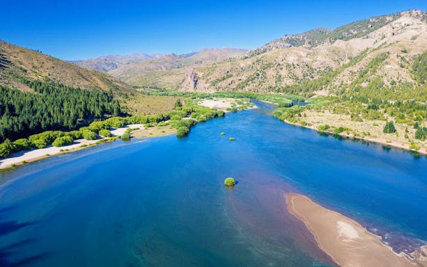 Panoramic view of a turquoise Patagonian lake with surrounding mountains and forests.