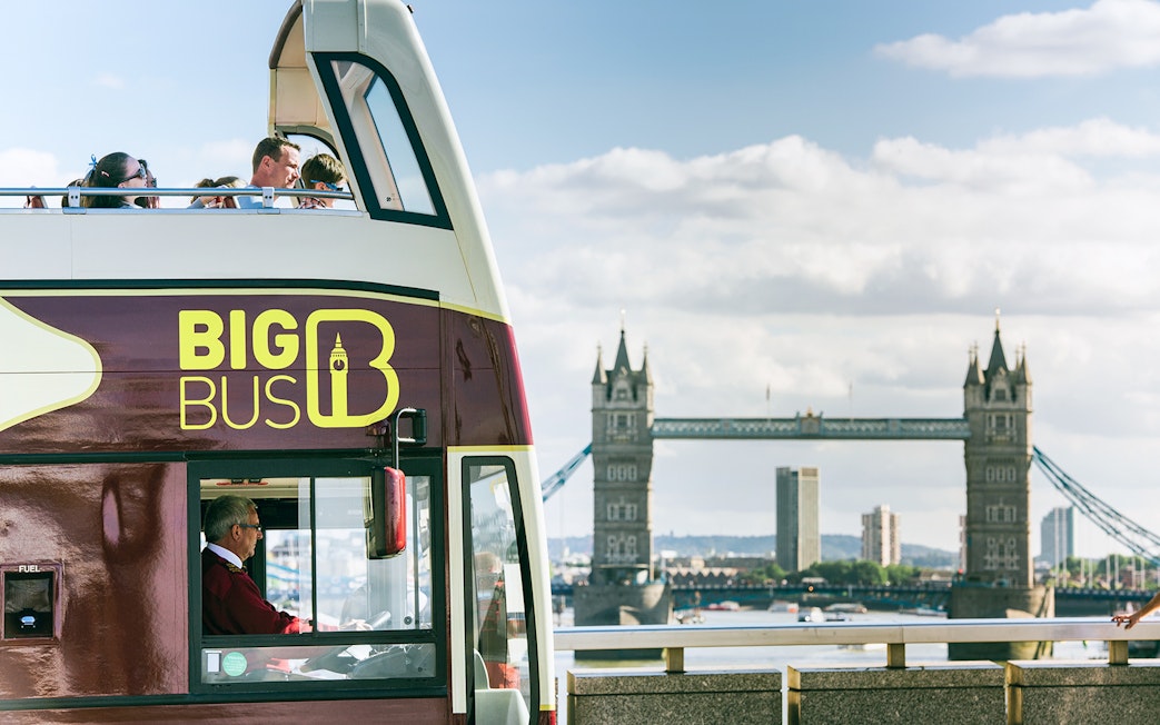 Open-top Big Bus London tour passing by Tower Bridge.