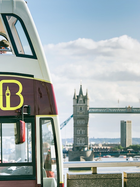 Open-top Big Bus London tour passing by Tower Bridge.