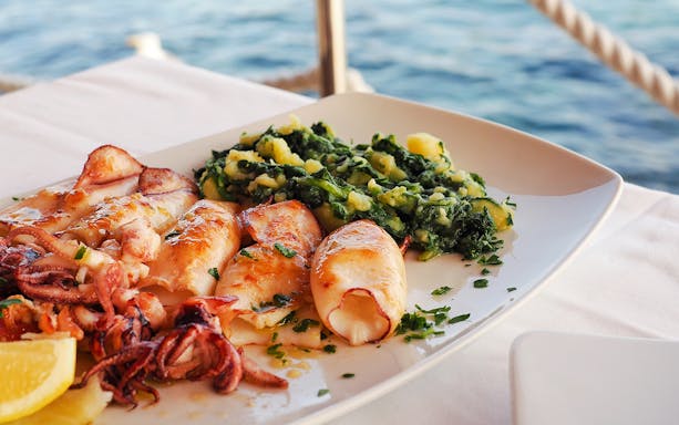 Grilled squid with greens served on a boat tour in Blue Lagoon, Duga Bay, Trogir.
