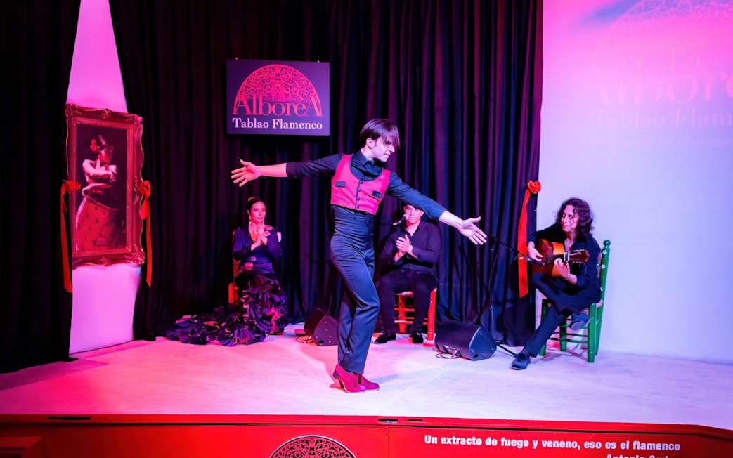 Flamenco dancer performing at La Alboreá in Granada with musicians on stage.