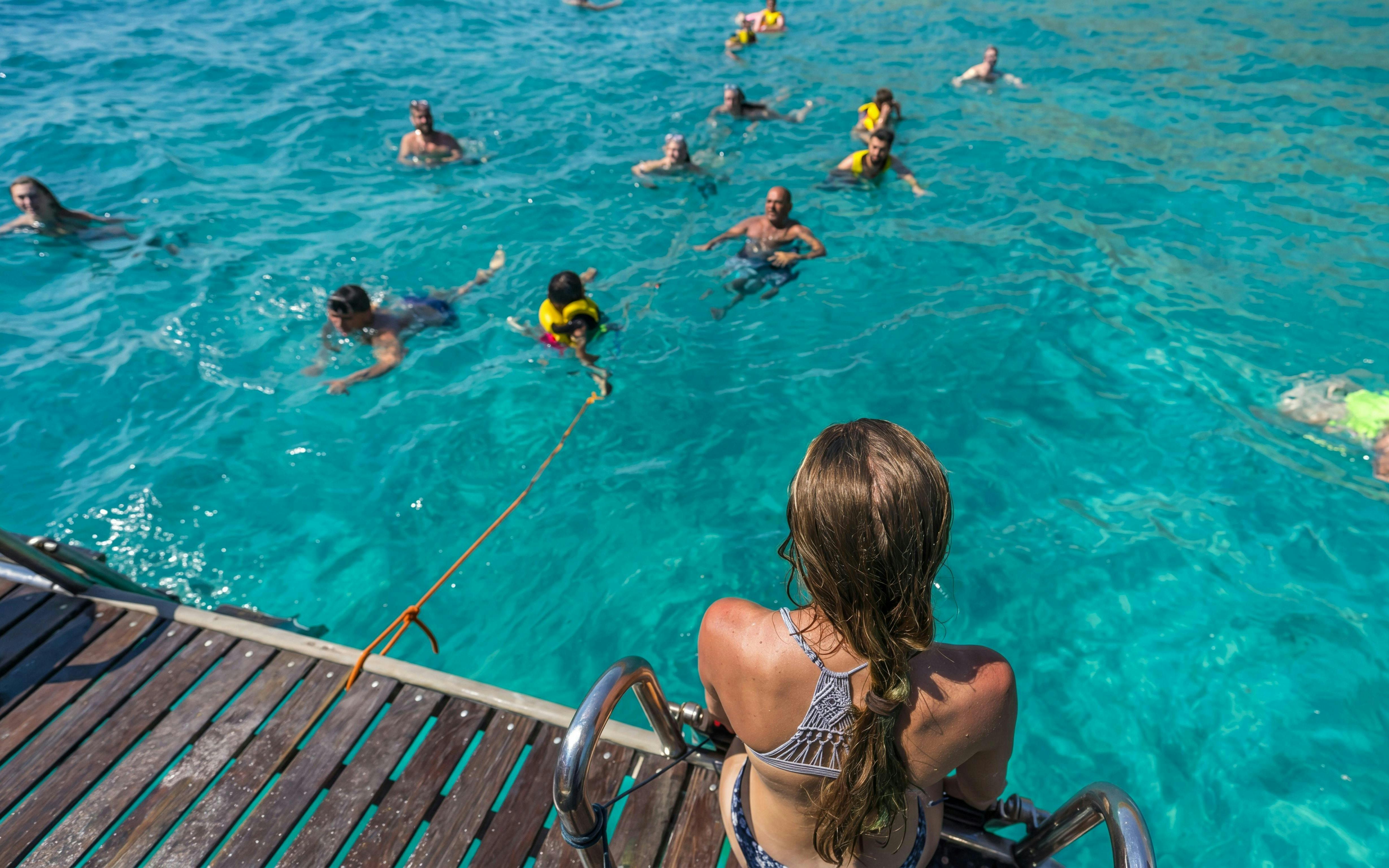 Tourists swimming in clear water during Superman boat tour in Mallorca.