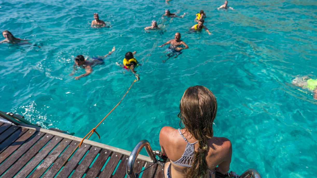 Tourists swimming in clear water during Superman boat tour in Mallorca.