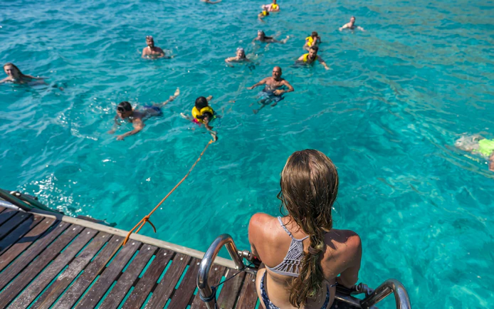 Tourists swimming in clear water during Superman boat tour in Mallorca.