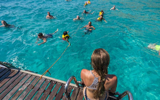 Tourists swimming in clear water during Superman boat tour in Mallorca.
