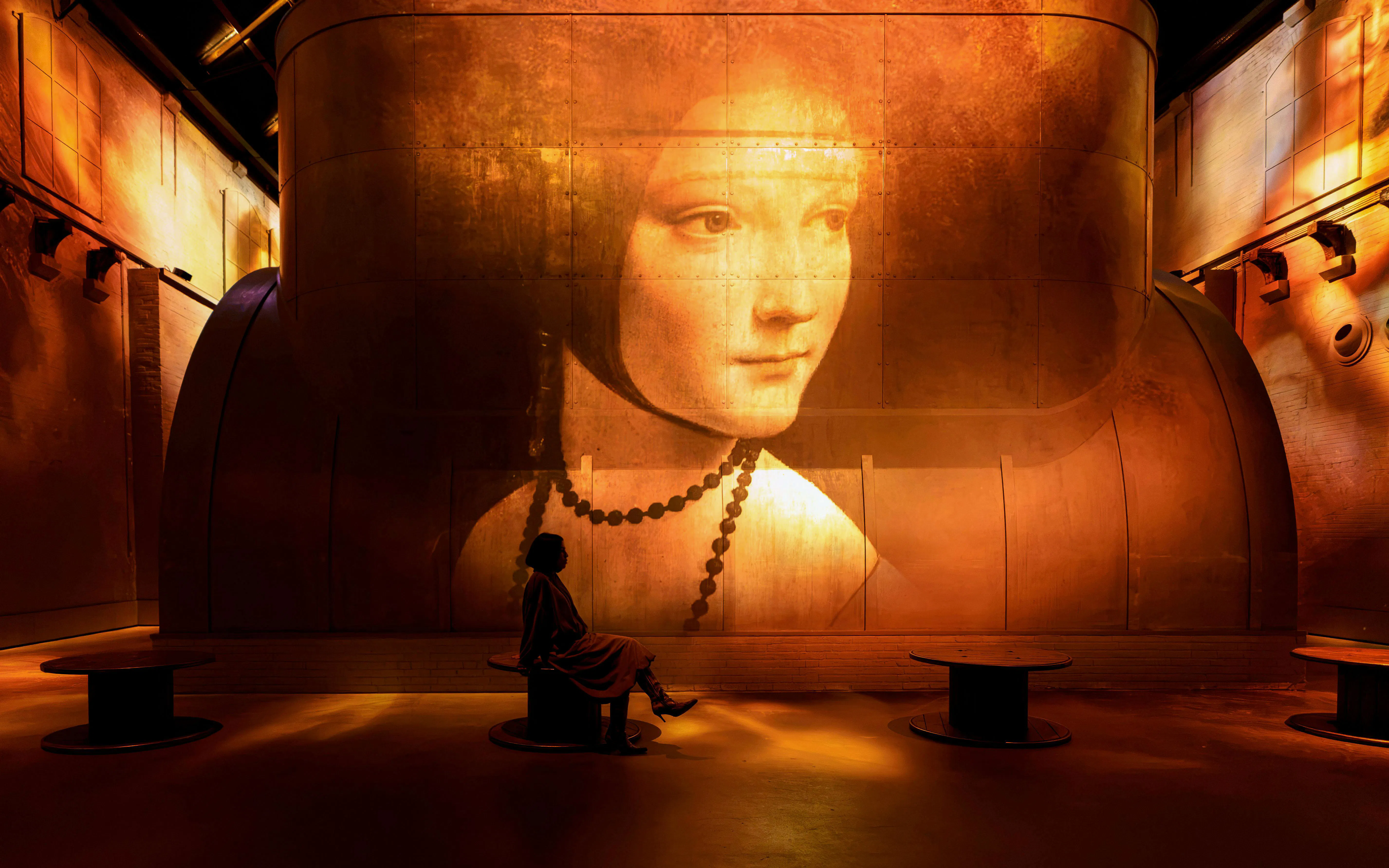 Projection of "Lady with an Ermine" at Fabrique des Lumières, visitor seated in foreground.
