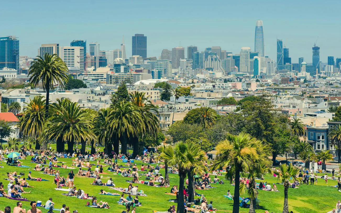 People relaxing in Dolores Park with San Francisco skyline in the background.