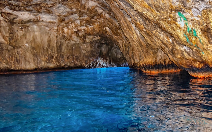 Blue waters inside Grotta Azzurra cave, Capri, with rocky walls reflecting light.
