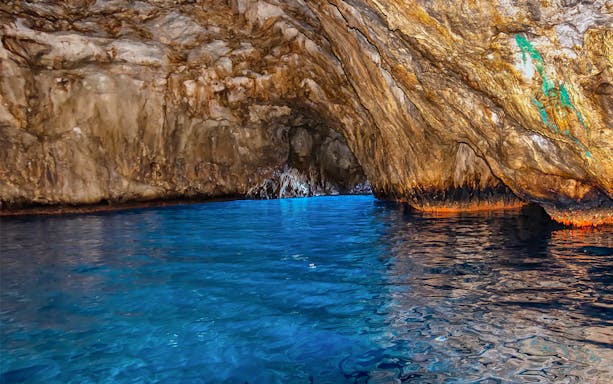 Blue waters inside Grotta Azzurra cave, Capri, with rocky walls reflecting light.