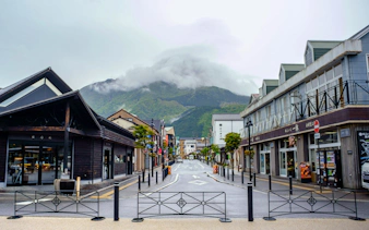 Shopping street with shops and mountain view near Yufuin Station, Kyushu.