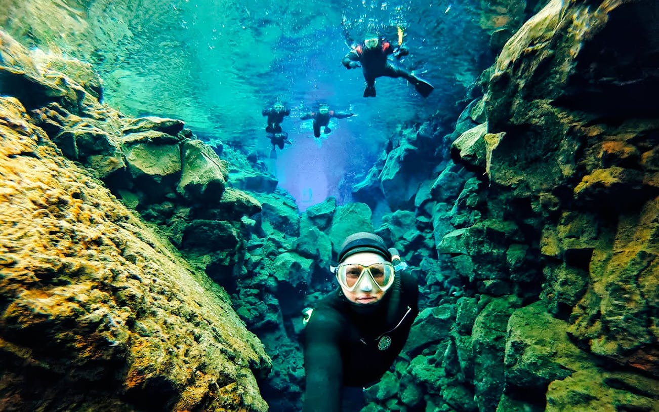 Snorkelers exploring the clear waters and rocky formations of Silfra in Iceland.