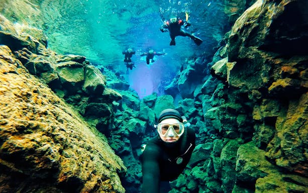 Snorkelers exploring the clear waters and rocky formations of Silfra in Iceland.