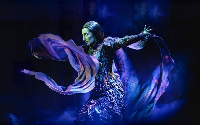 Performer in dramatic pose during Wicked musical scene.