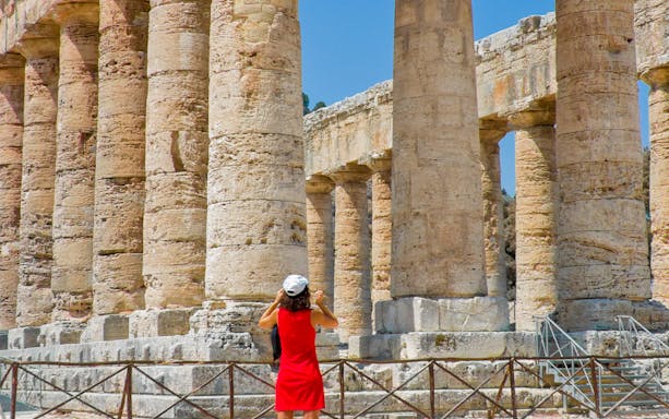 Visitor exploring the ancient columns of the Temple of Segesta in Segesta Archeological Park.