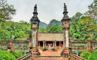 Xuan Thuy Temple entrance with ornate pillars and lush greenery, Hoa Lu, Vietnam.