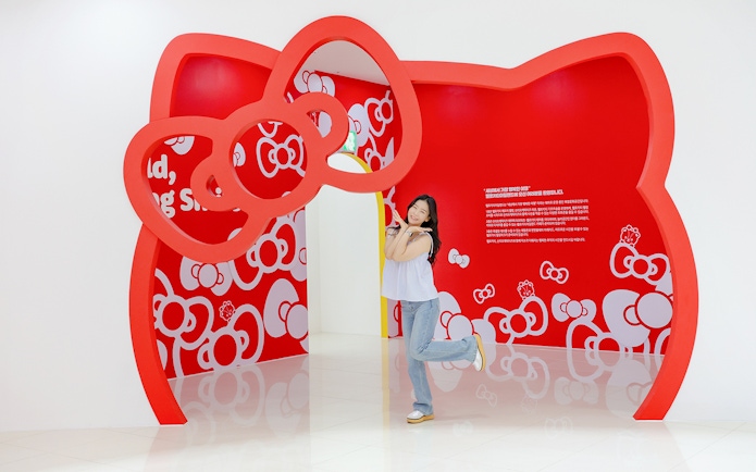 Tourist posing under red Hello Kitty arch at Hello Kitty Island.